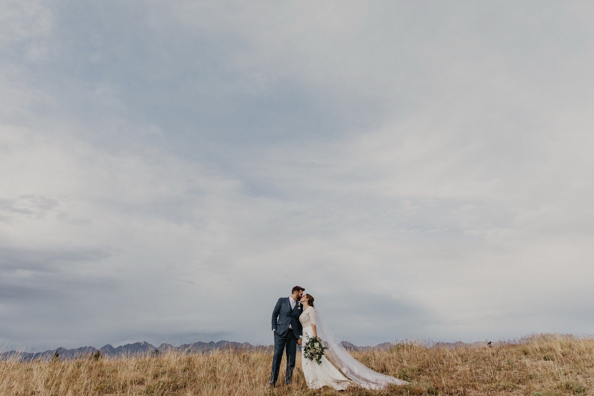 A couple on their wedding day, kissing on a mountaintop above Vail, Colorado
