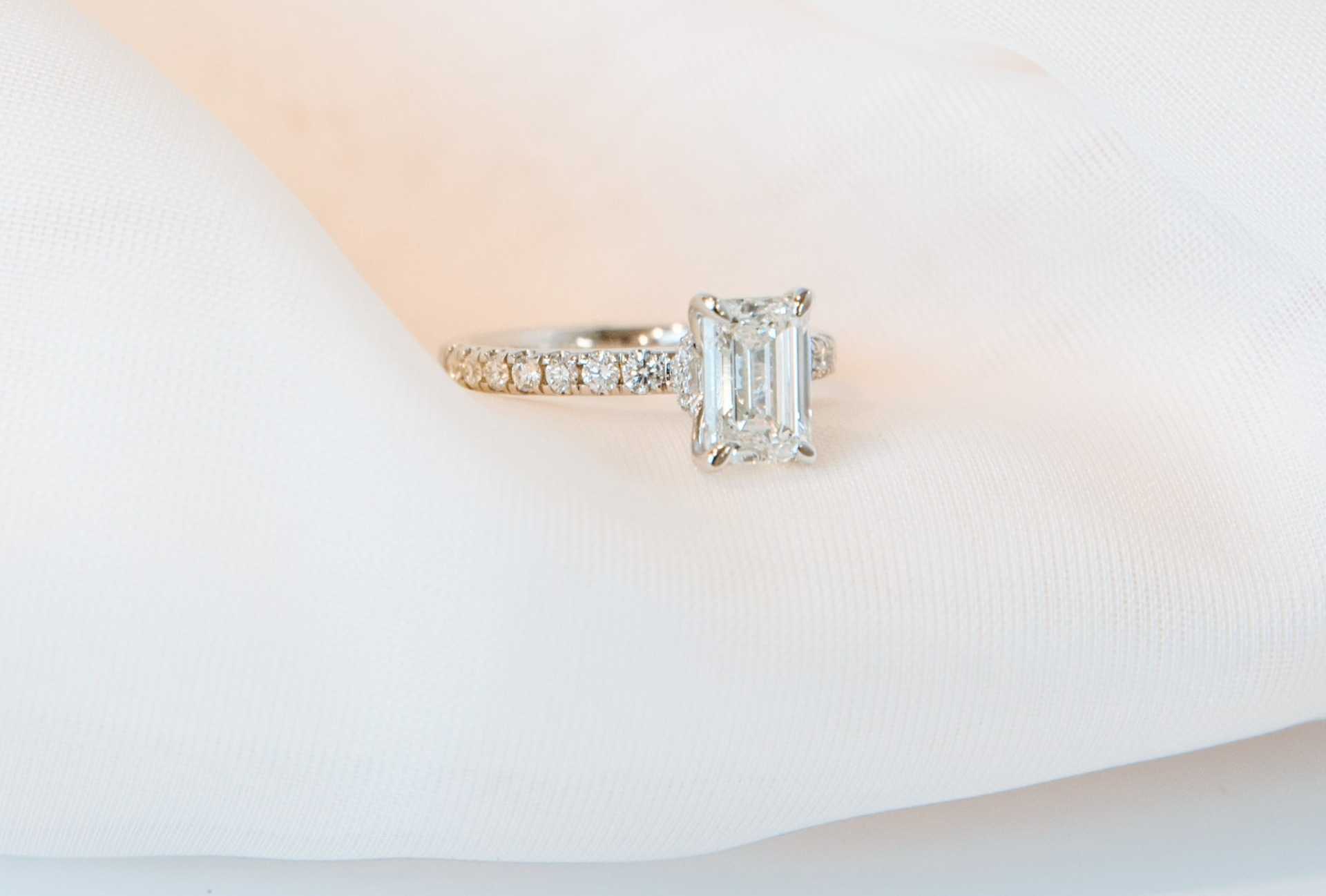 An emerald-cut diamond ring on white silk